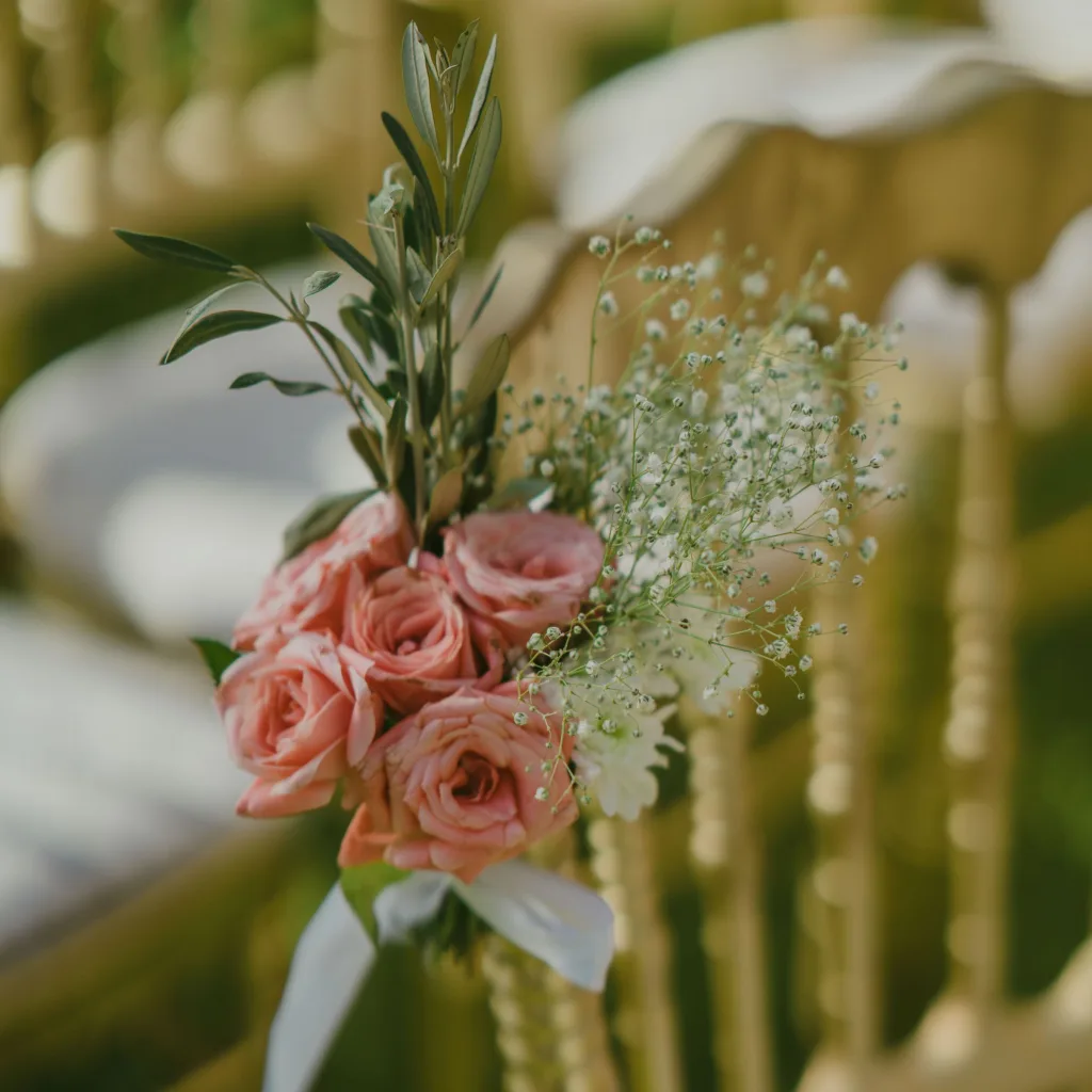Bouquet de roses et de gypsophile noué au dossier d’une chaise de cérémonie, lors d’un mariage à Marrakech