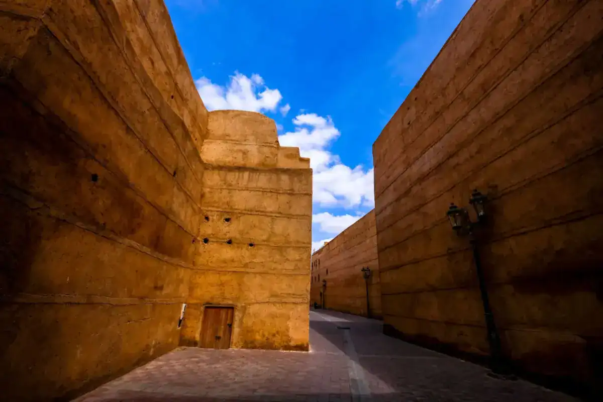 Hauts murs ocre d’une ruelle de Marrakech sous un ciel bleu