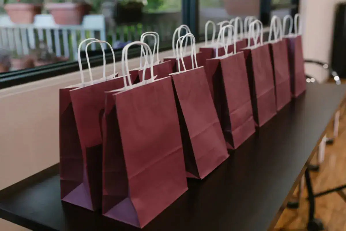 Rangée de pochettes cadeau en papier bordeaux alignées sur une table