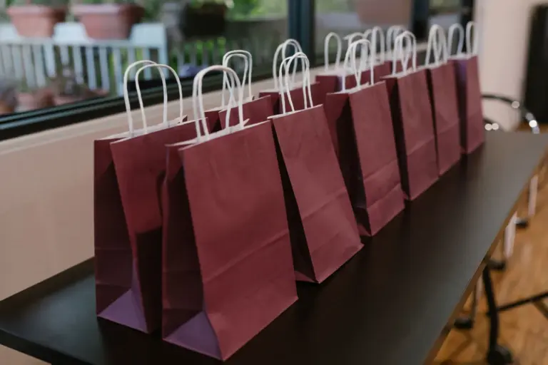 Rangée de pochettes cadeau en papier bordeaux alignées sur une table