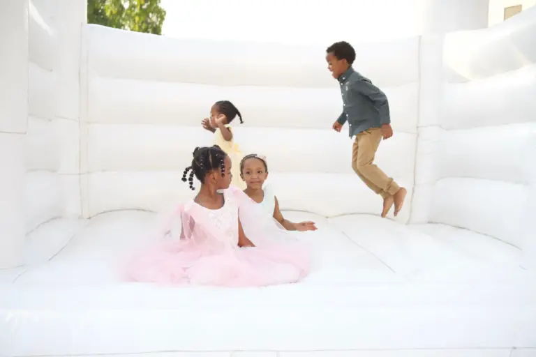 Enfants en tenue de fête jouant dans un château gonflable blanc pendant une réception