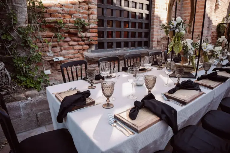 Longue table de mariage dressée dans une cour intérieure aux murs de brique et de végétation