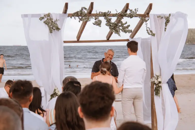 Cérémonie de mariage sur la plage, les mariés sous une arche de voilages face à l'océan