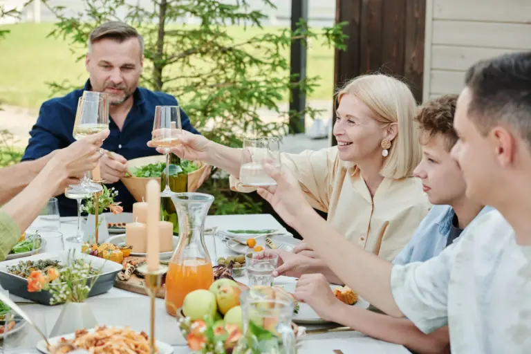 Plusieurs générations d'une même famille trinquant autour d'une table dressée dans le jardin