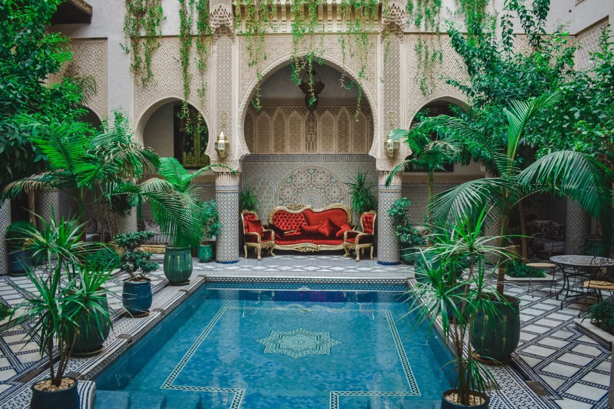 Patio marocain à arcades, verdure et bassin décoré