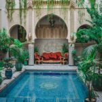 Patio marocain à arcades, verdure et bassin décoré