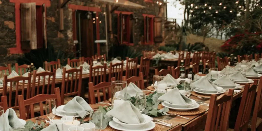 Longues tables dressées en extérieur sous des guirlandes lumineuses pour un dîner de fête