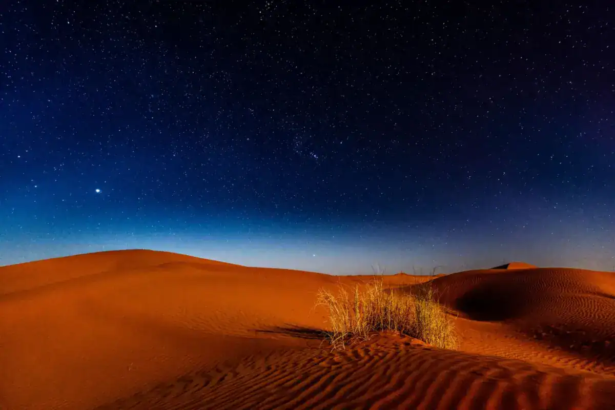 Dunes du désert sous un ciel étoilé, à la tombée de la nuit