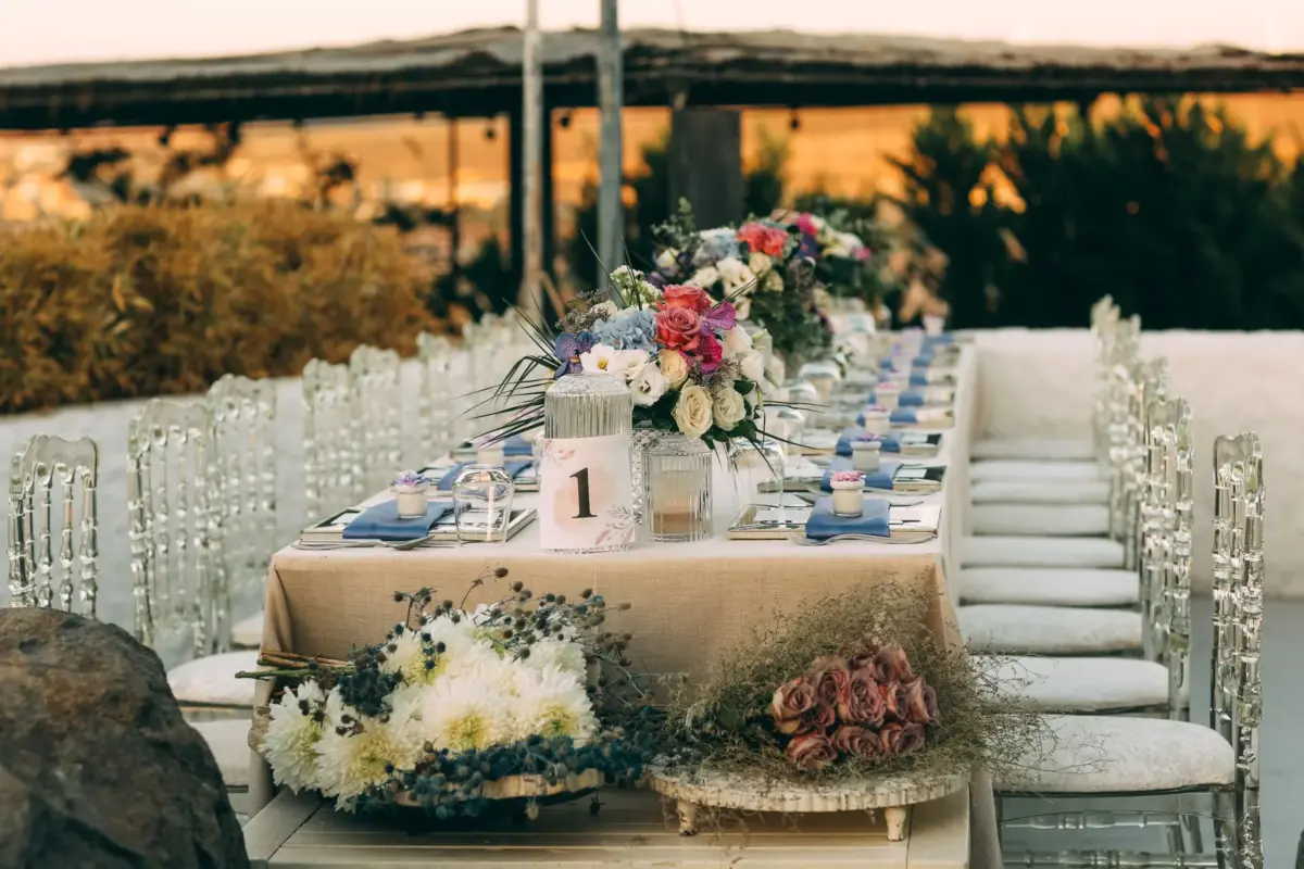 Wedding banquet table with flowers and crystal chairs at sunset