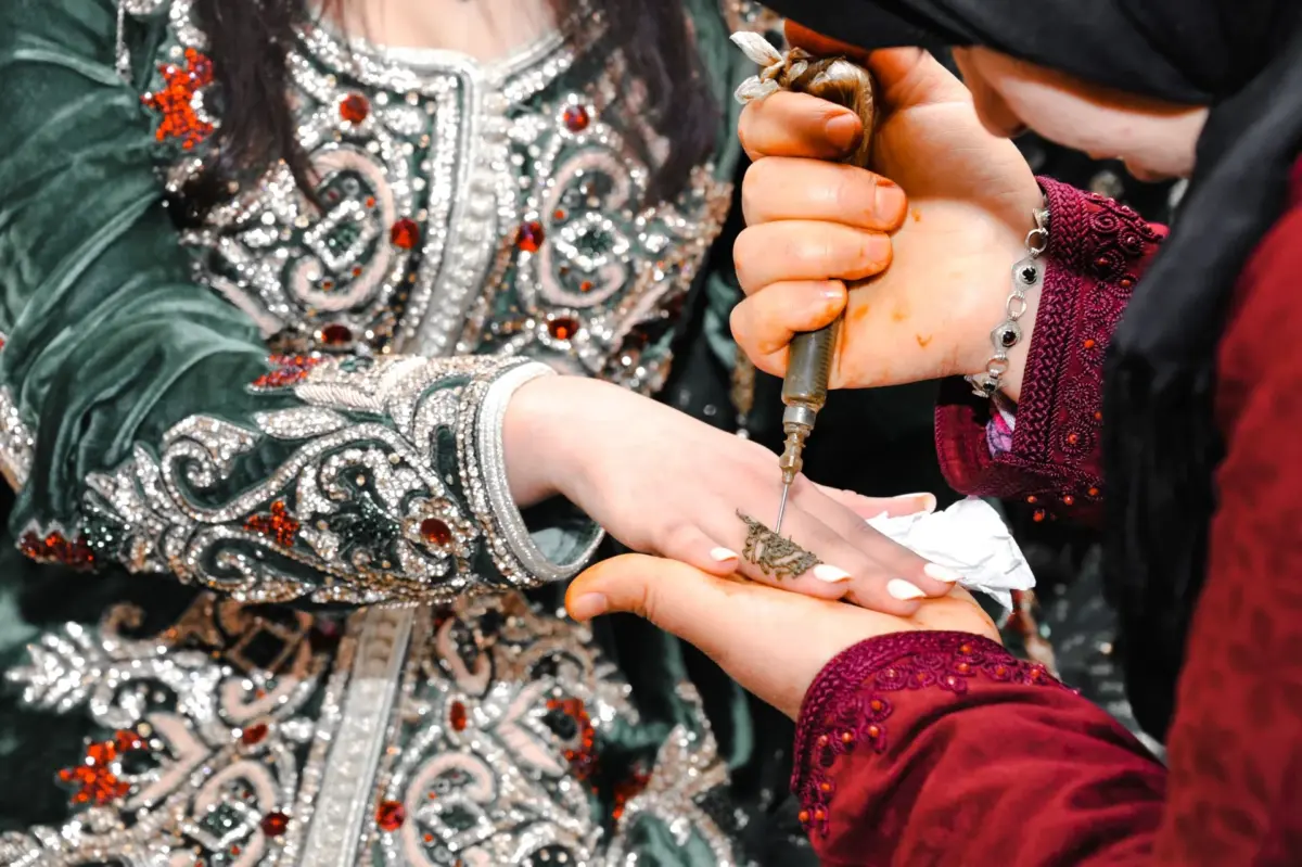 Henna being applied to the hand of a bride in an embroidered Moroccan caftan