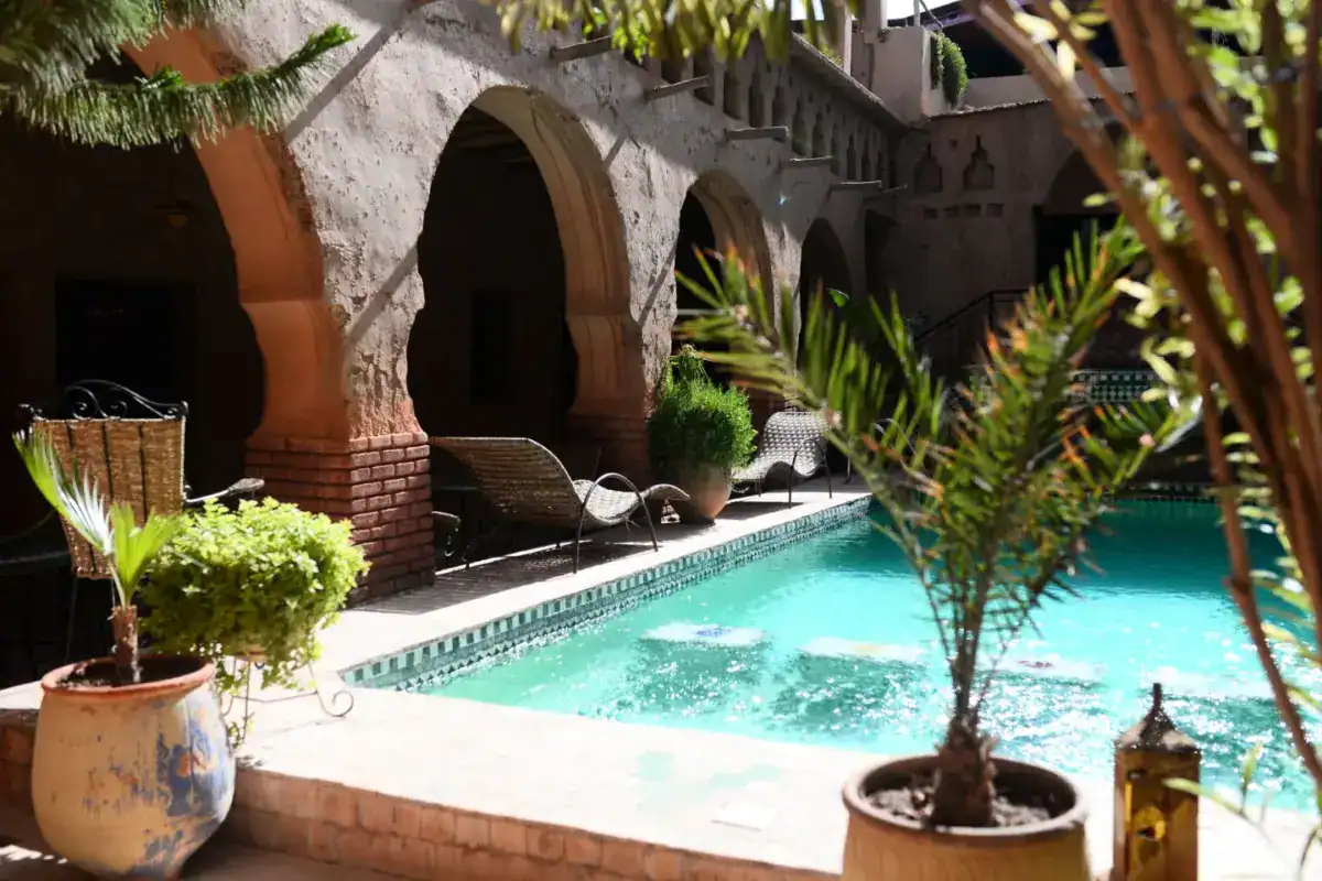 Patio d’un riad, bassin turquoise et arcades de terre ocre
