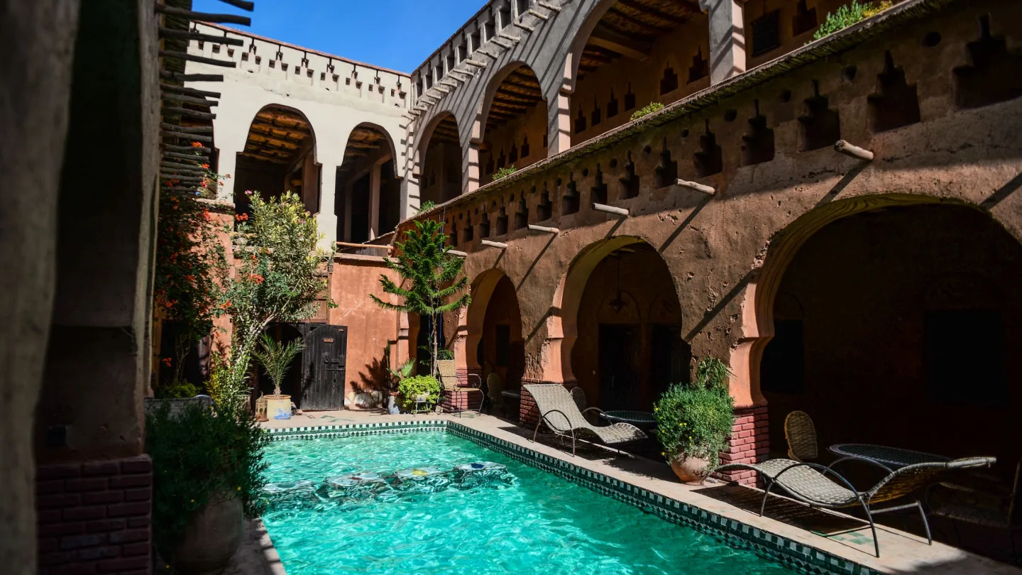 Cour à arcades et bassin d’une demeure traditionnelle marocaine, entre terre ocre et végétation