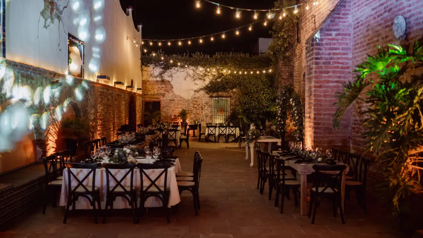 Cour de riad illuminée de guirlandes, tables dressées pour une réception le soir