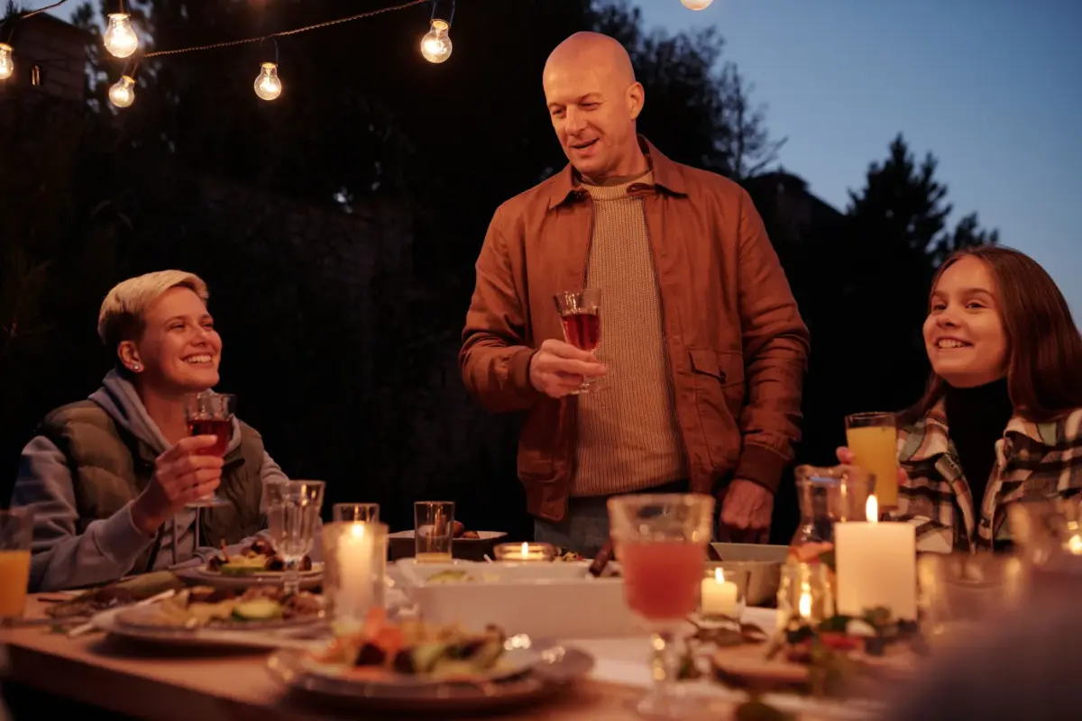 Groupe portant un toast autour d'un dîner en plein air à la tombée de la nuit