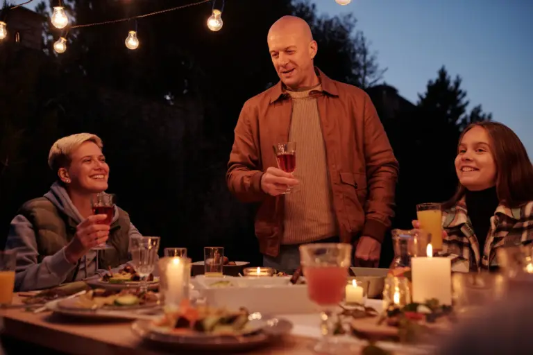 Groupe portant un toast autour d'un dîner en plein air à la tombée de la nuit