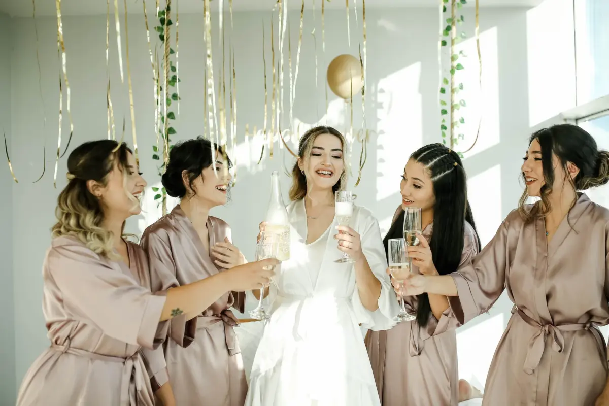 Future mariée et ses amies en peignoir trinquant au champagne