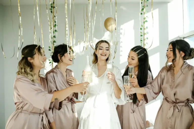 Future mariée et ses amies en peignoir trinquant au champagne