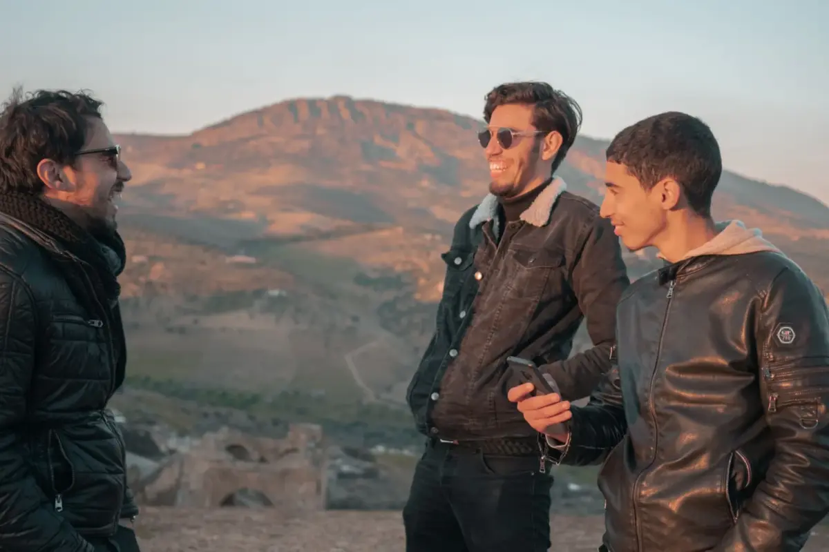 Trois amis qui rient en plein air face aux montagnes au Maroc