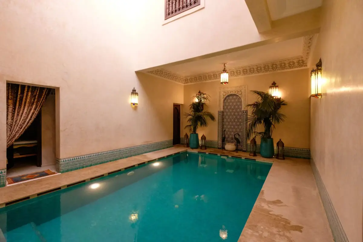 Bassin intérieur éclairé de lanternes dans un riad de Marrakech