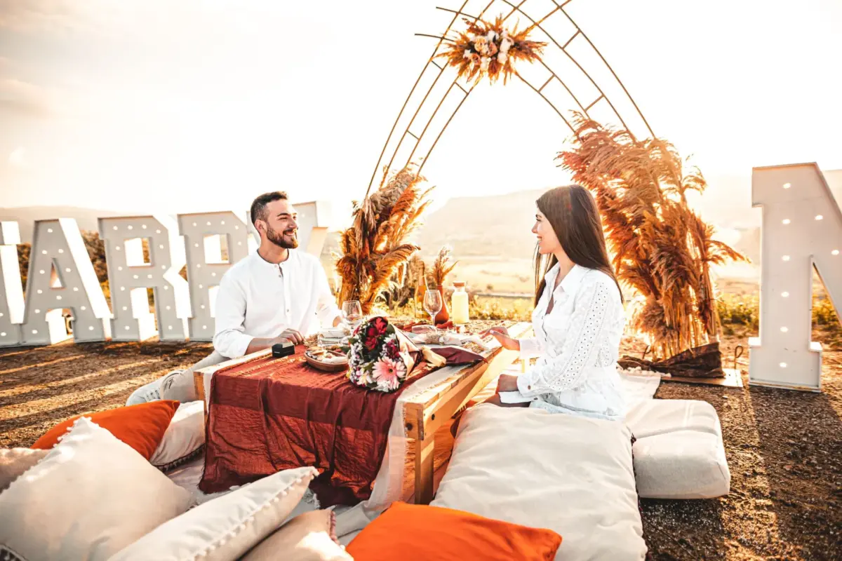 Dîner surprise en amoureux en plein air : table basse, coussins et lettres lumineuses
