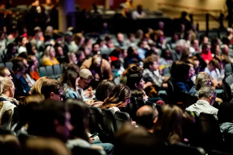 Public nombreux assis dans les gradins d'un auditorium pendant un congrès
