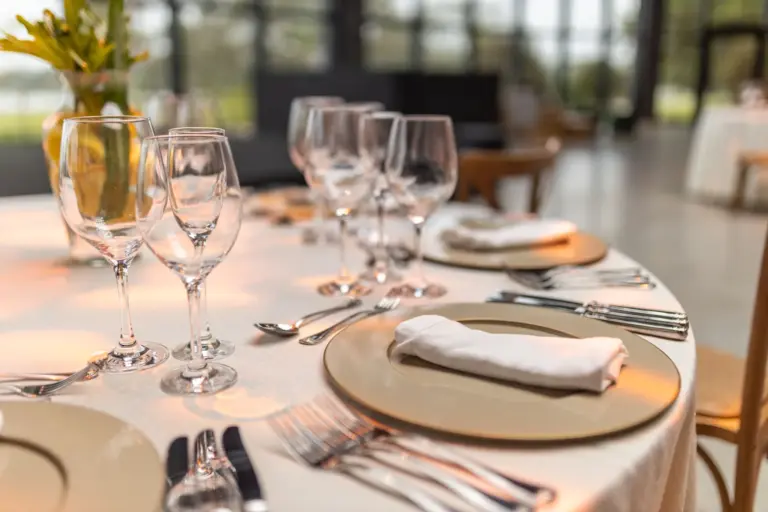 Table de déjeuner de séminaire dressée, assiettes de présentation dorées et verres à pied