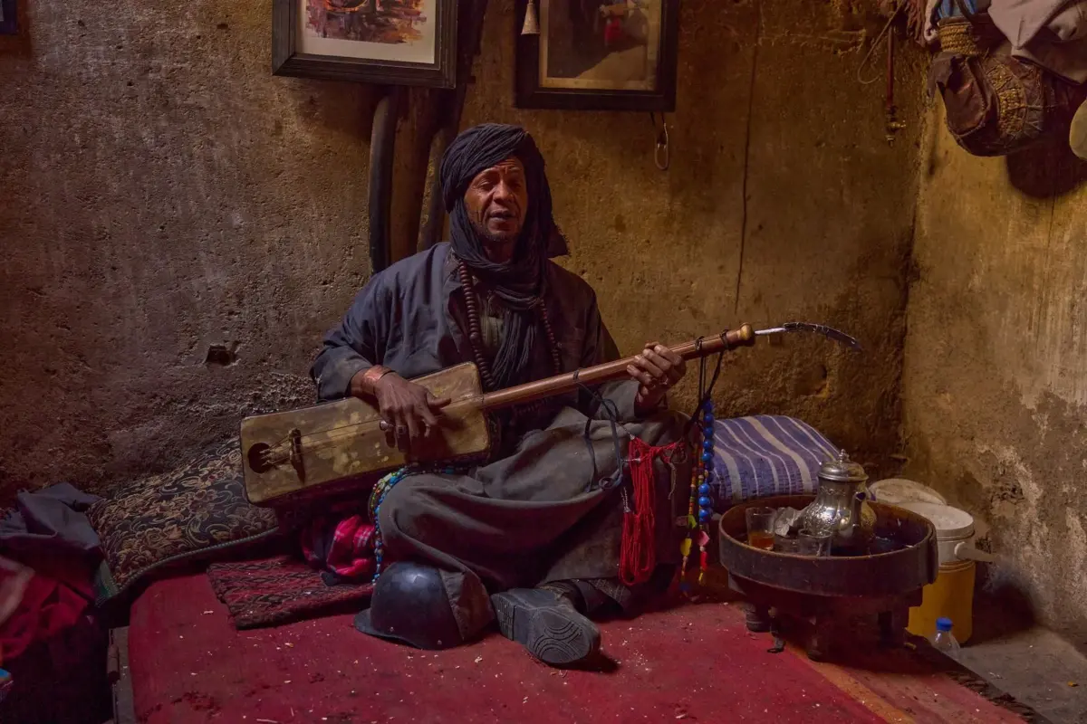 Musicien gnaoua qui joue du guembri assis dans une maison de Marrakech