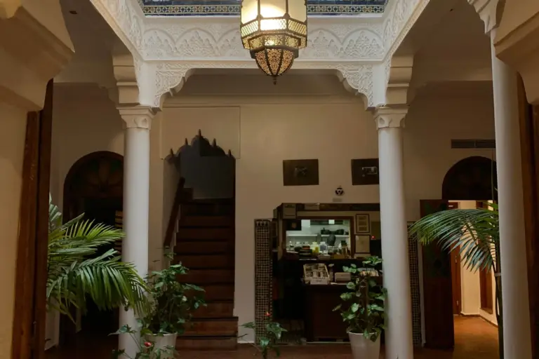 Patio d'un riad-hôtel de Marrakech avec colonnes blanches et lanterne, accueil d'une formation