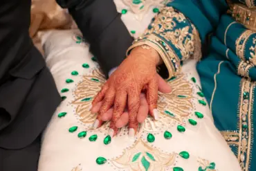 Mains de mariés marocains en tenue traditionnelle brodée, la mariée aux mains ornées de henné