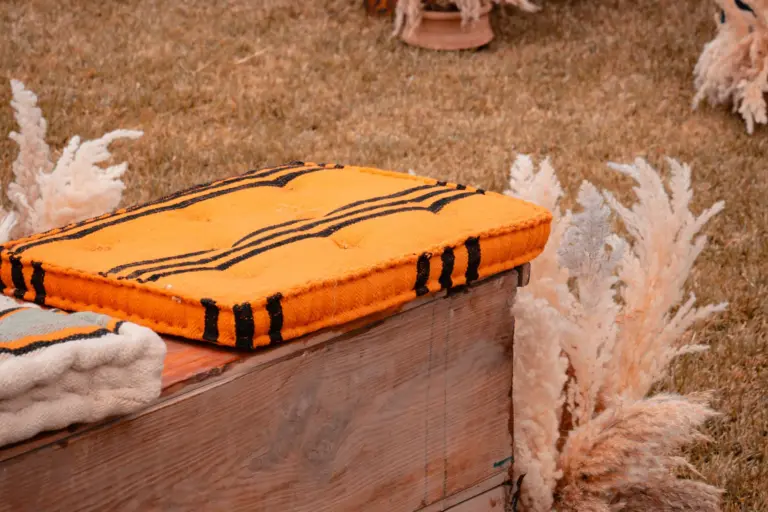 Bancs en bois, coussins orange et pampas pour une cérémonie de mariage bohème à Marrakech