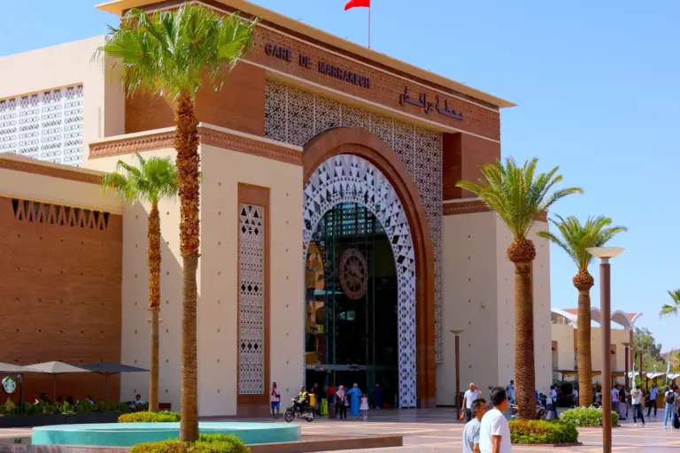 Façade de la gare ferroviaire de Marrakech et son parvis bordé de palmiers