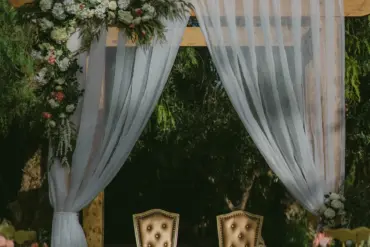 Arche de cérémonie drapée de voilages et de fleurs dans un jardin de Marrakech
