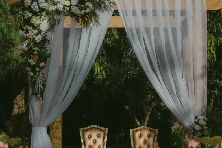 Arche de cérémonie drapée de voilages et de fleurs dans un jardin de Marrakech