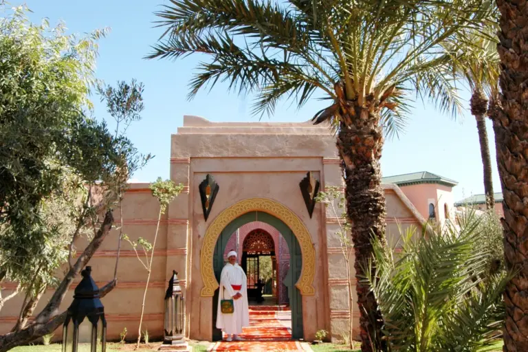 Allée de tapis rouge menant à l'entrée d'un hôtel entouré de palmiers à Marrakech