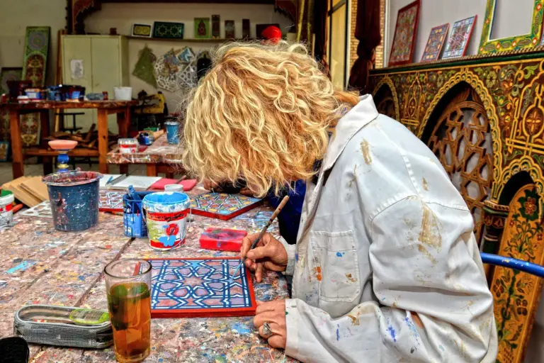 Artiste peignant un motif géométrique marocain dans un atelier à Fès