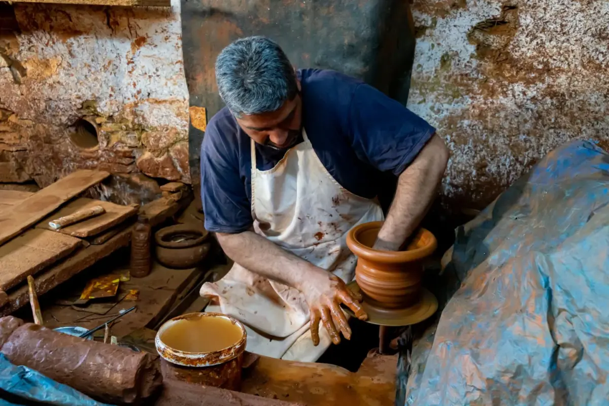 Artisan potier façonnant un pot sur son tour, dans un atelier