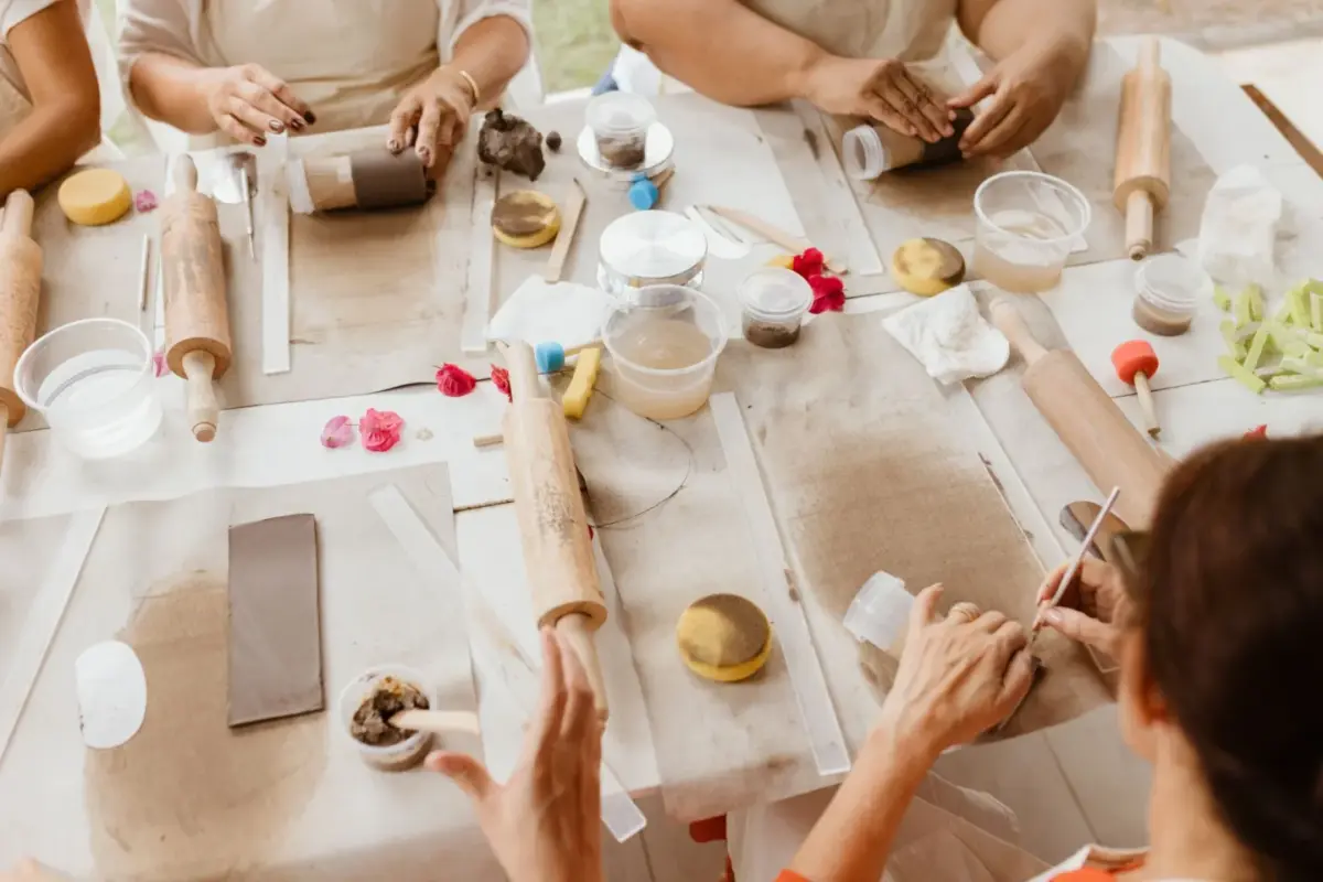 Collègues autour d'une table d'atelier de modelage, argile et outils