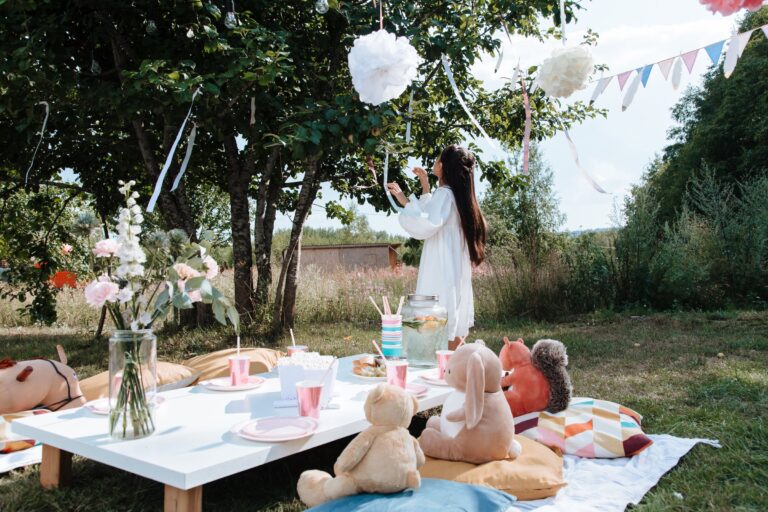 Goûter d'enfants dans un jardin, table basse, peluches et guirlandes