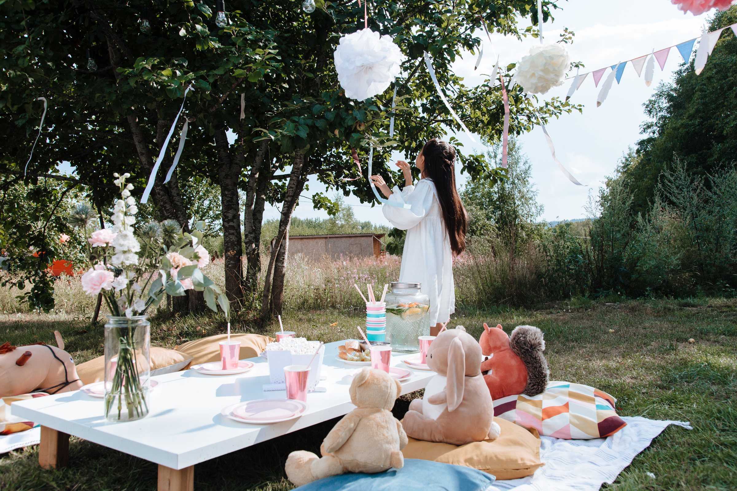 Goûter d'enfants dans un jardin, table basse, peluches et guirlandes