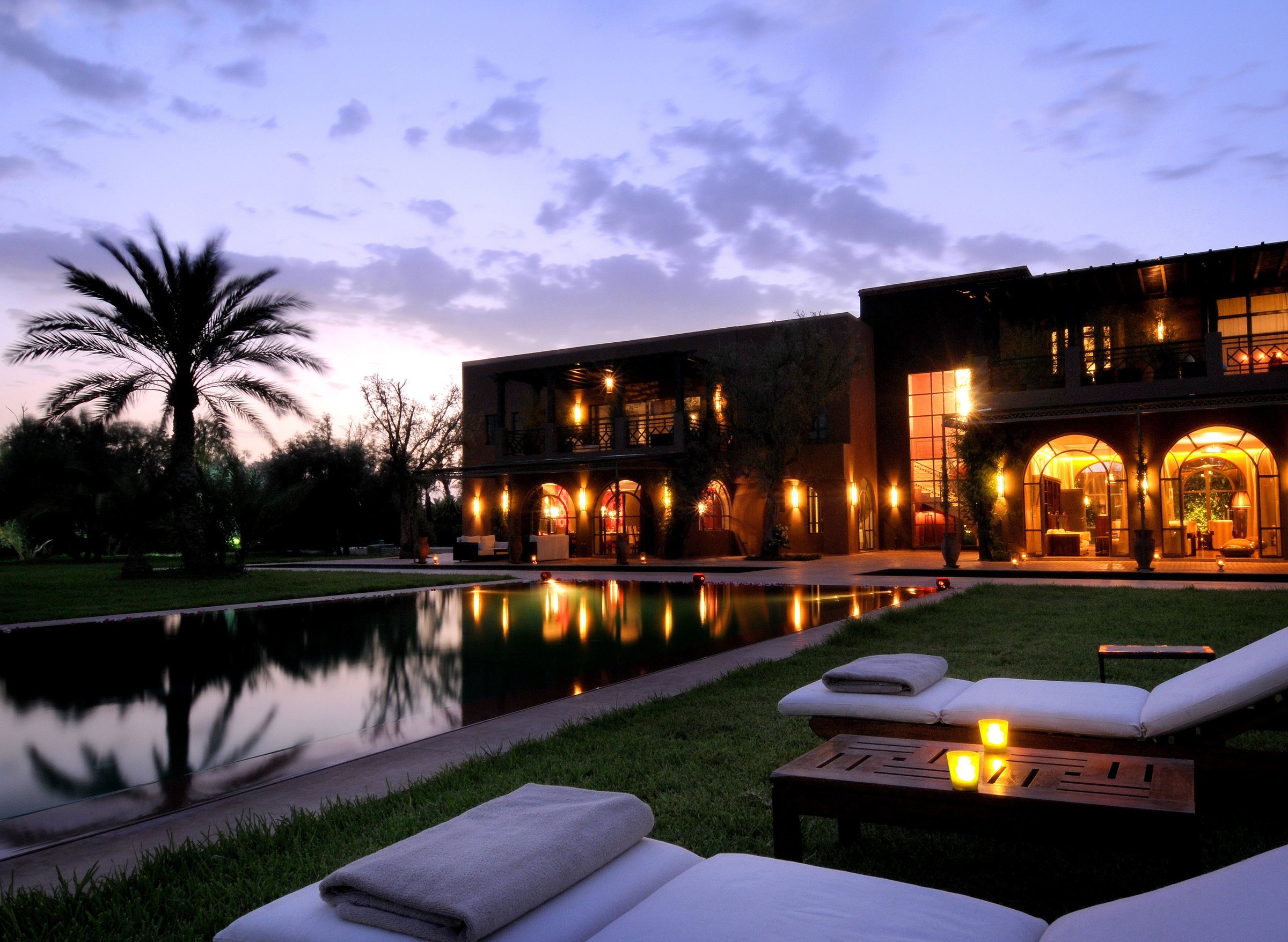 Hôtel de Marrakech éclairé au crépuscule avec bassin et palmier