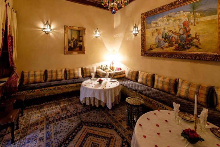 Salon marocain avec banquettes, tables dressées et pétales de rose