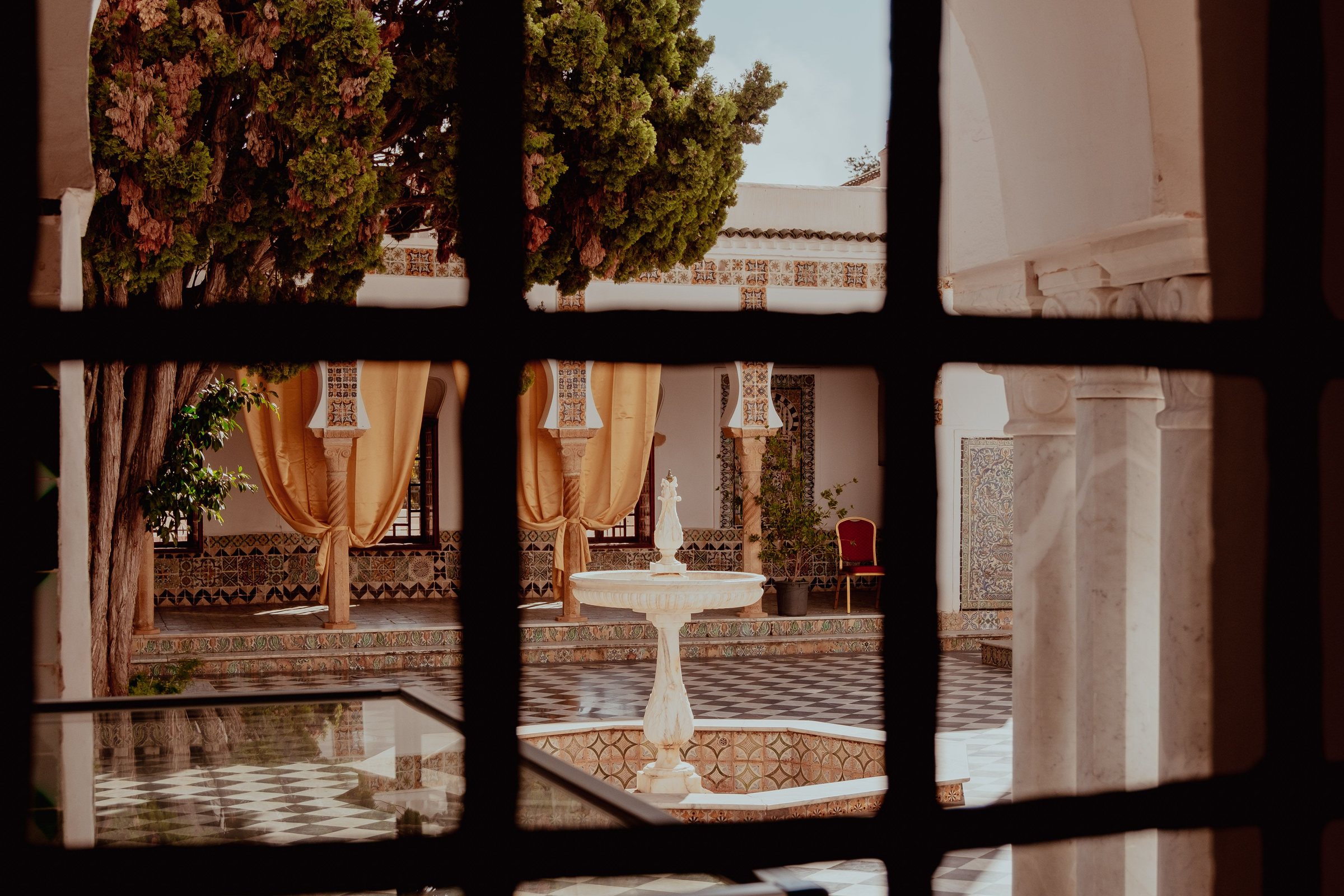 Vue sur un patio mauresque à fontaine à travers une fenêtre à croisillons