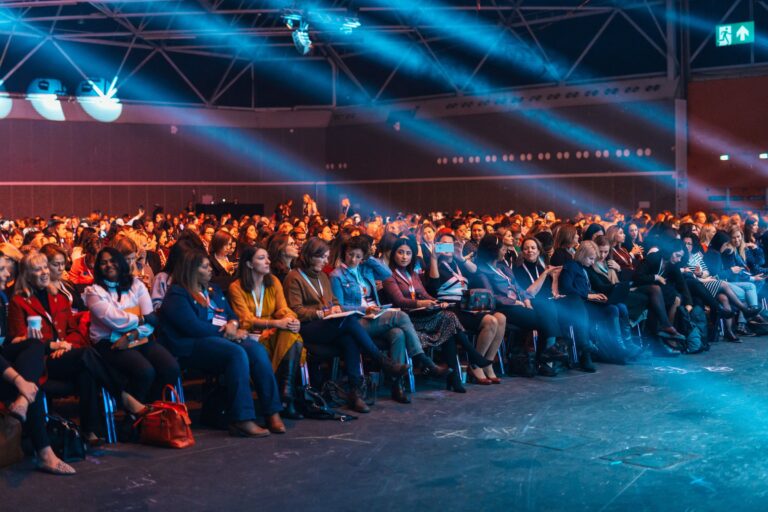 Public assis dans une grande salle de conférence éclairée