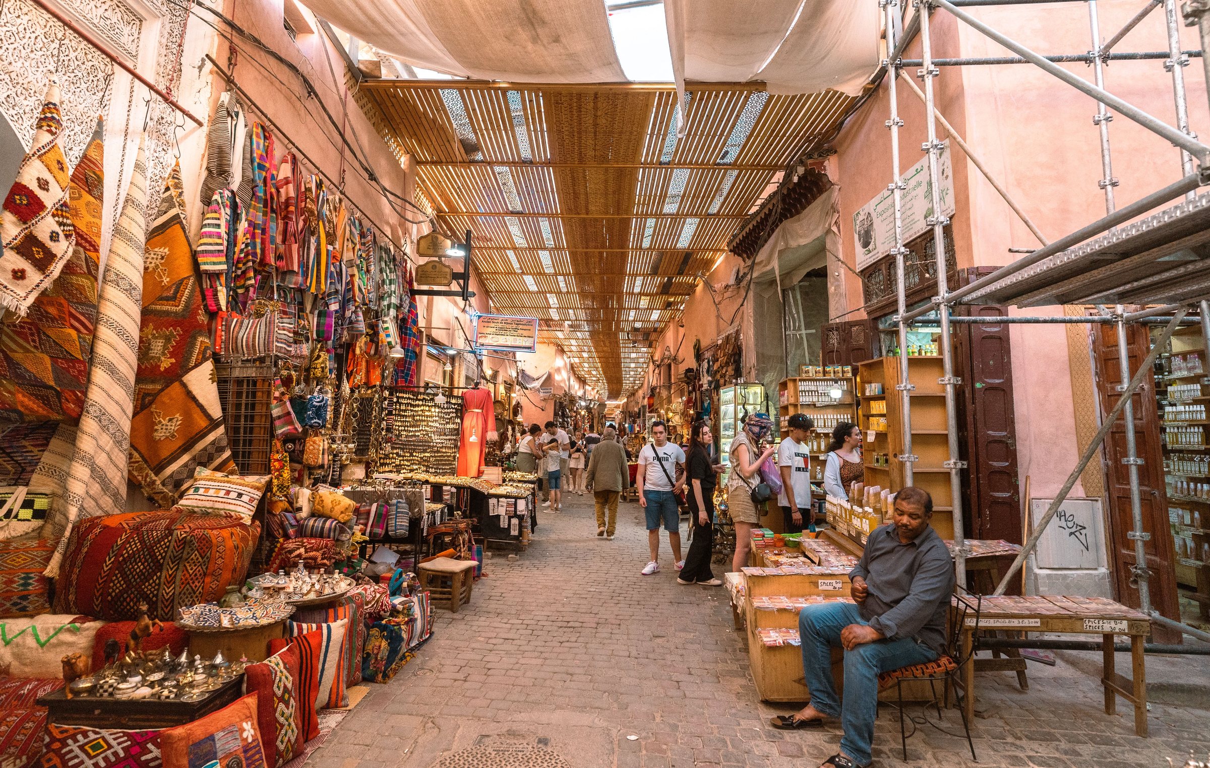Ruelle couverte du souk de Marrakech, tapis, coussins et étals