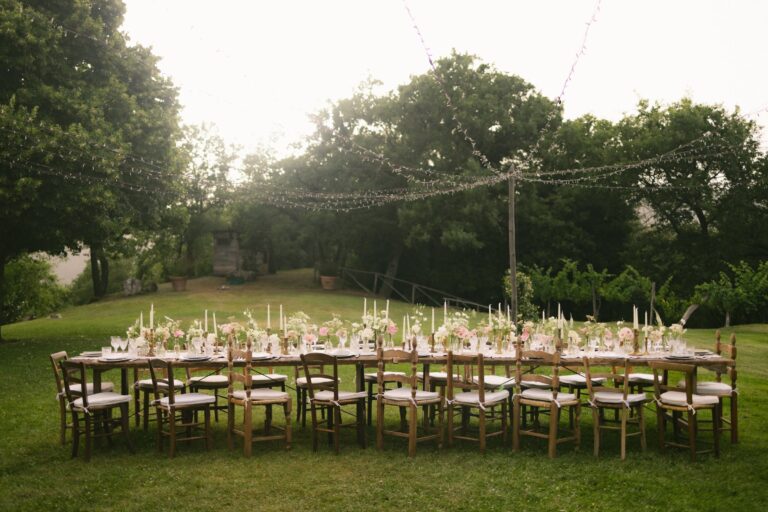 Longue table de réception dressée dans un jardin sous guirlandes