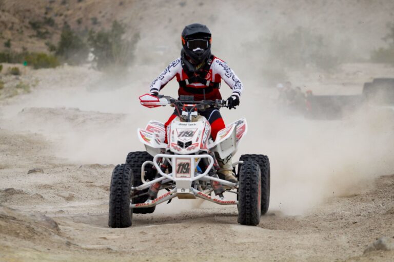 Pilote de quad en casque intégral et tenue de protection dans la poussière