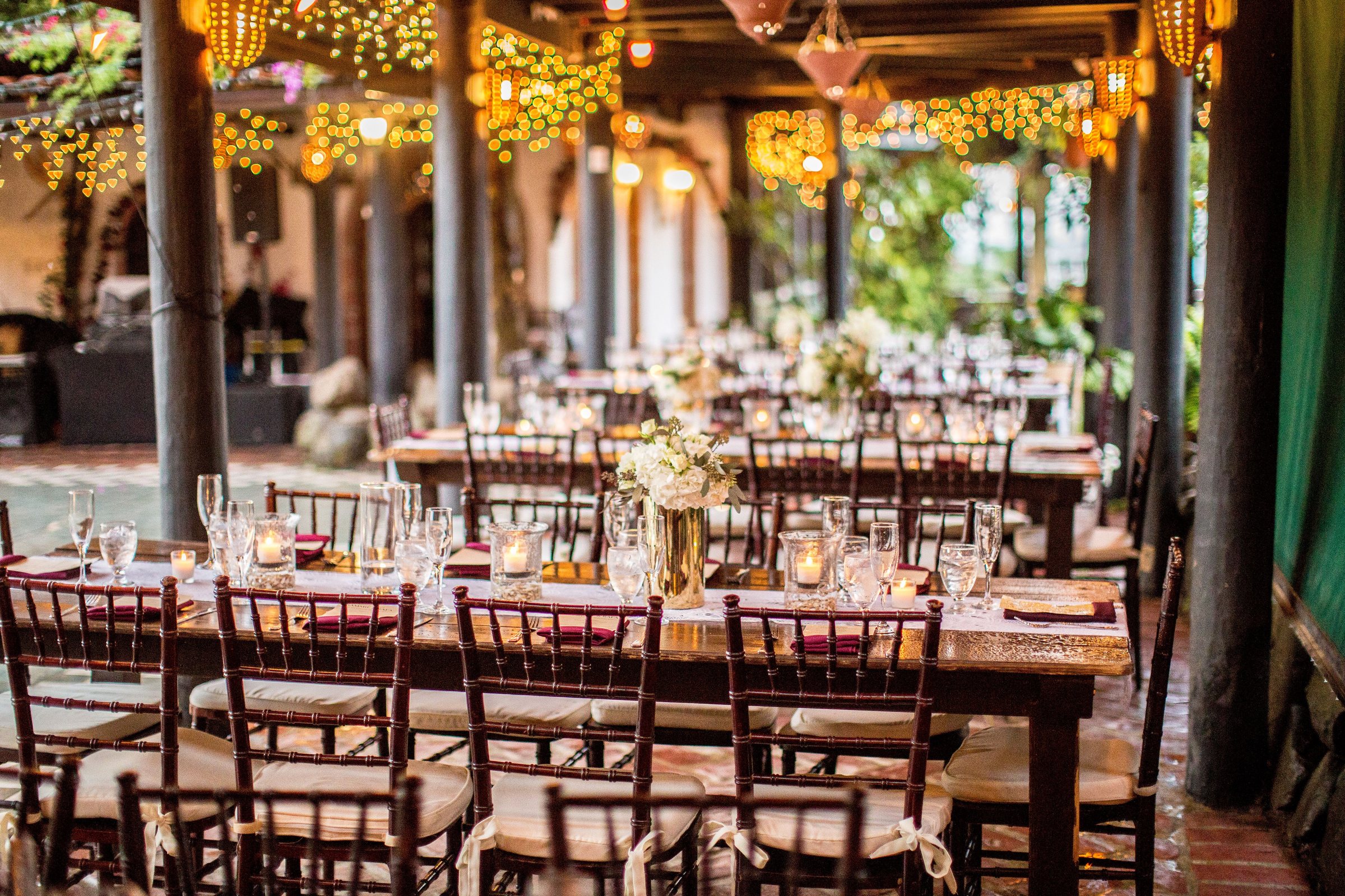 Longues tables de banquet sous une pergola éclairée de guirlandes