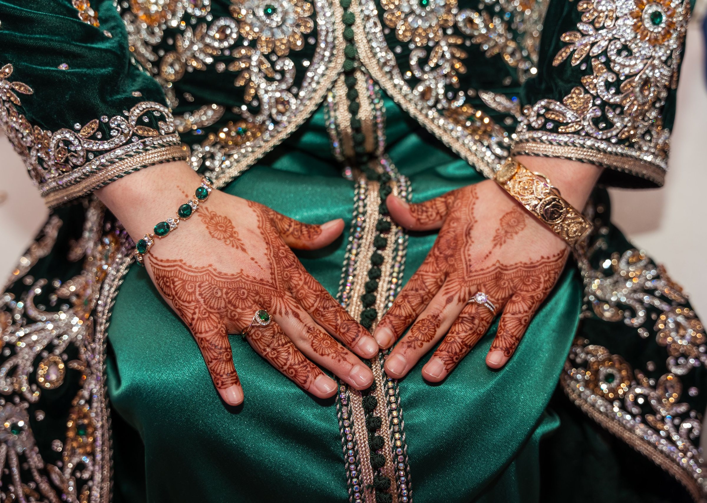 Mains ornées de henné sur un caftan vert brodé