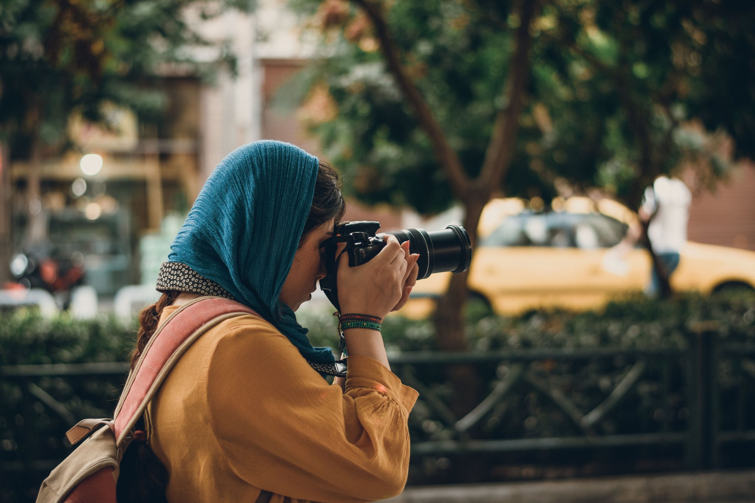 Femme en foulard photographiant une rue de Marrakech
