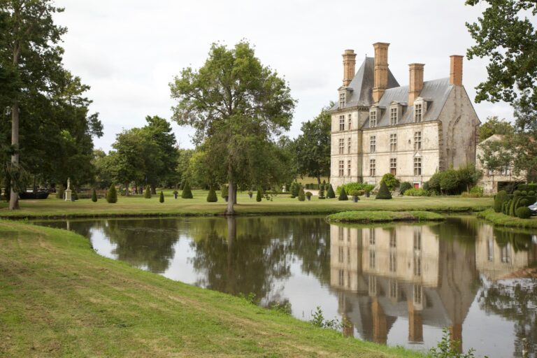 Château entouré d'un parc, reflété dans un étang
